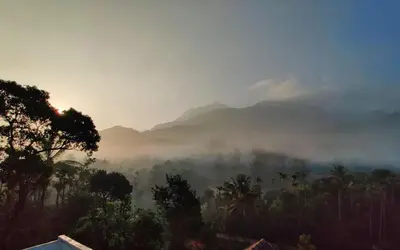 a misty view of a valley with mountains in the background at Padikkal Bungalow in Vayittiri
