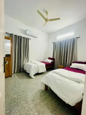 a bedroom with two beds and a ceiling fan at D Villas in Kunnamangalam