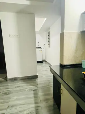a kitchen with white walls and a wooden floor at D Villas in Kunnamangalam