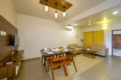 a kitchen and living room with a table and chairs at Focuz Habitat Hotel And Ayurveda in Malappuram