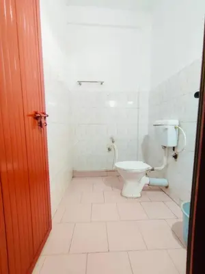 a bathroom with a toilet in a white room at Omega Tourist Home in Trichūr