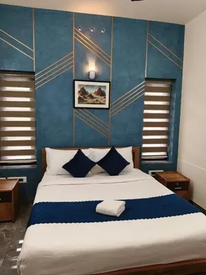 a bedroom with a large bed with blue walls at Ecostay inn in Sultan Bathery