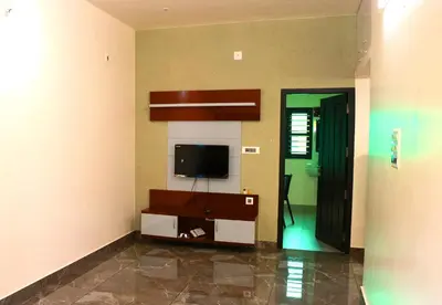 a living room with a flat screen tv in the corner at Ecostay inn in Sultan Bathery