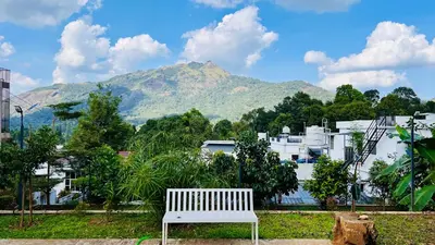 a white bench in front of a city with a mountain at Hill View Heights Wayanad in Meppādi
