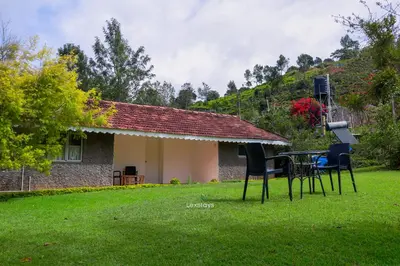 a house with a table and chairs in the yard at 42 Green Pastures By Lexstays -Tea Estate Experience in Coonoor