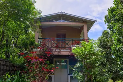 a house with a balcony with red flowers on it at 42 Green Pastures By Lexstays -Tea Estate Experience in Coonoor