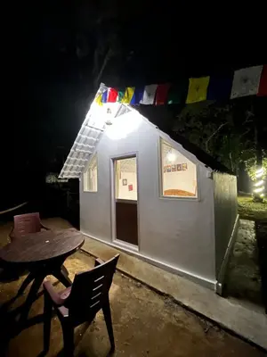 a small house at night with a table and chairs at TauSco Homestay & Campsite - Coorg in Madikeri