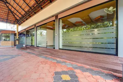 a building with glass windows and a brick walkway at Super Hotel O Thrissur Near Thrissur Medical College in Trichūr