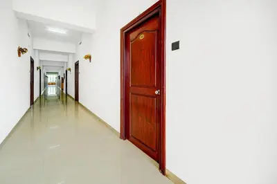 a hallway with a wooden door and white walls at Super Hotel O Thrissur Near Thrissur Medical College in Trichūr