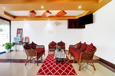 a living room with chairs and a table and a tv at Super Hotel O Thrissur Near Thrissur Medical College in Trichūr