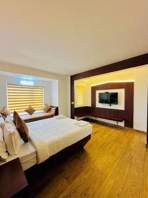 a bedroom with two beds and a flat screen tv at Kanavu Valley View in Ooty