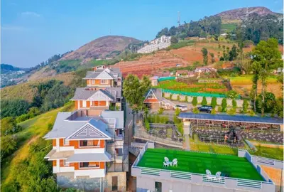 a group of buildings with a hill in the background at Kanavu Valley View in Ooty