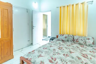 a bedroom with a bed and a yellow curtain at Be My Guest in Kozhikode