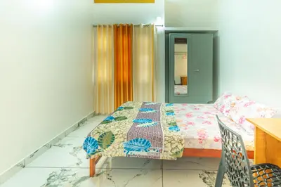 a bedroom with a bed and a table and chair at Be My Guest in Kozhikode