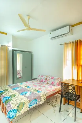 a bedroom with a bed and a desk and a table at Be My Guest in Kozhikode