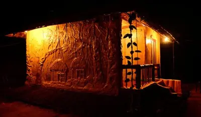 a building with a stone wall with a window at Greenways Tree House and Mud House in Chekadi