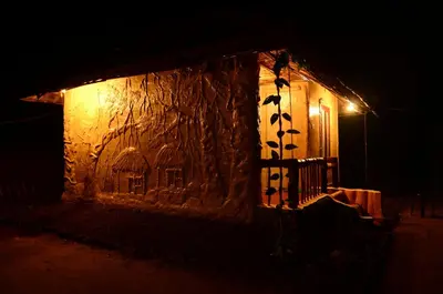 a stone building with a bench in front of it at night at Greenways Tree House and Mud House in Chekadi