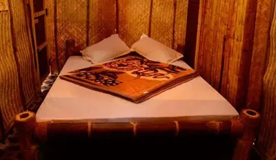 a small bed in a wooden room at Greenways Tree House and Mud House in Chekadi