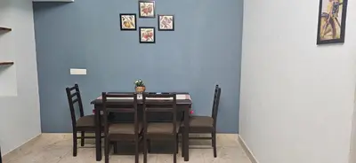 a dining room table with chairs and a blue wall at SHIs Aathira 2bhk Heart of Coimbatore in Coimbatore