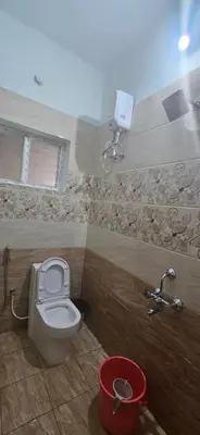 a bathroom with a toilet and a red bucket at SHIs Aathira 2bhk Heart of Coimbatore in Coimbatore