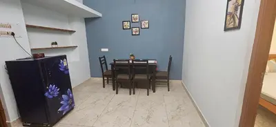 a dining room with a table and chairs and a refrigerator at SHIs Aathira 2bhk Heart of Coimbatore in Coimbatore