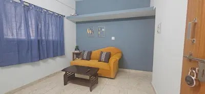 a living room with a yellow couch and a table at SHIs Aathira 2bhk Heart of Coimbatore in Coimbatore