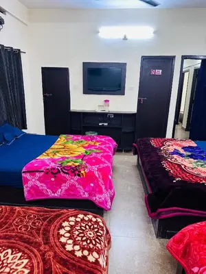 a room with two beds and a flat screen tv at G Mount inn in Munnar