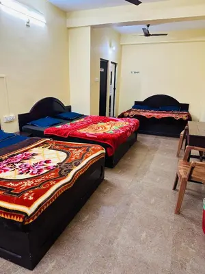 a room with two beds and a table and chairs at G Mount inn in Munnar