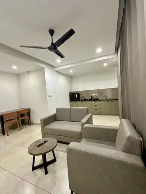 a living room with two couches and a table at Portico Service Apartments in Kozhikode