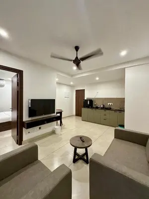 a living room with a couch and a flat screen tv at Portico Service Apartments in Kozhikode