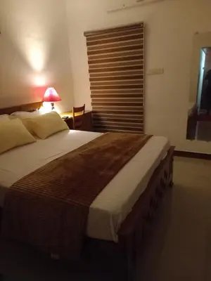 a bedroom with a large bed with a lamp and a window at Stains holidayhome & party floor, Cherai beach in Pallipuram