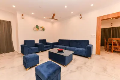 a living room with blue couches and a table at Hotel Shine International in Mysore