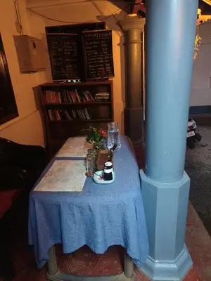 a table with a blue table cloth and a pillar at Perch Next door in Kannur