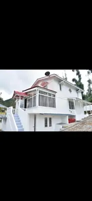a white house with a balcony and stairs at Attuvam Valley in Kodaikānāl