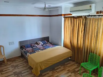 a bedroom with a bed and a green chair at Konar Mandabam in Palani