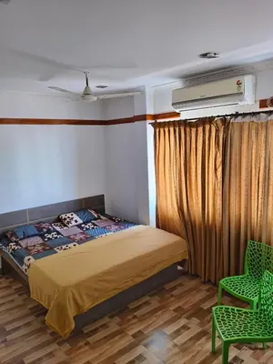 a bedroom with a bed and a green chair at Konar Mandabam in Palani