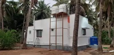 a white building with palm trees in front of it at Hotel Rams in Coimbatore