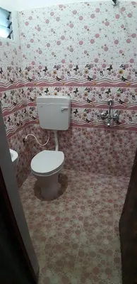 a bathroom with a toilet and floral wallpaper at Hotel Rams in Coimbatore