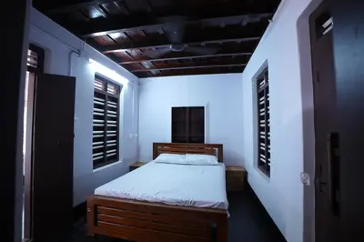 a bedroom with a bed in a room with windows at Koodapuzha House Chalakudy in Kizhake Chālakudi