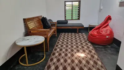 a room with two tables and a bench and a red bag at Koodapuzha House Chalakudy in Kizhake Chālakudi