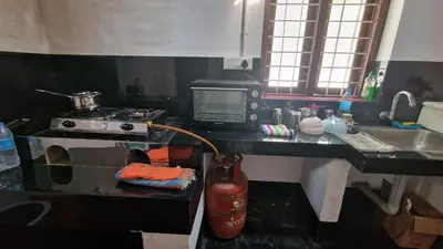 a kitchen with a counter with a stove and a sink at Koodapuzha House Chalakudy in Kizhake Chālakudi