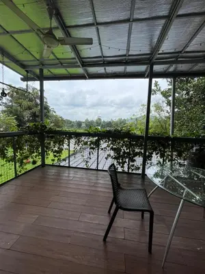 a glass table and a chair on a balcony with a view at River View Apartments a Pet Friendly Retreat in Ernakulam