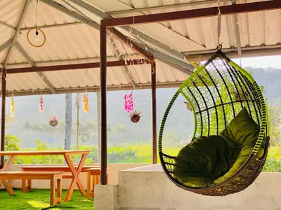 a hammock hanging from a tent with a table at Captain's Cove Home Stay in Sultan Bathery