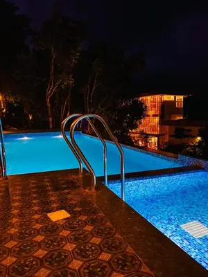 a swimming pool at night with a blue pool at Mizzle Resort in Padinjarathara