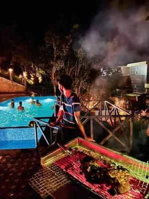 a man is standing next to a swimming pool at Mizzle Resort in Padinjarathara