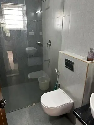 a bathroom with a toilet and a glass shower at Thottan house in Trichūr