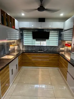 a large kitchen with wooden cabinets and a ceiling at Thottan house in Trichūr