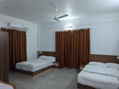 a hotel room with two beds and brown curtains at Jayalakshmi Residency in Vaduvanchal