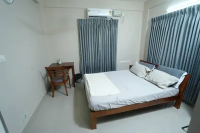 a bedroom with a bed and a chair and a table at A4, Melam, Hima Havens- 200 m from Guruvayoor Temple in Guruvāyūr