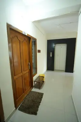 a hallway with a wooden door and a rug at A4, Melam, Hima Havens- 200 m from Guruvayoor Temple in Guruvāyūr